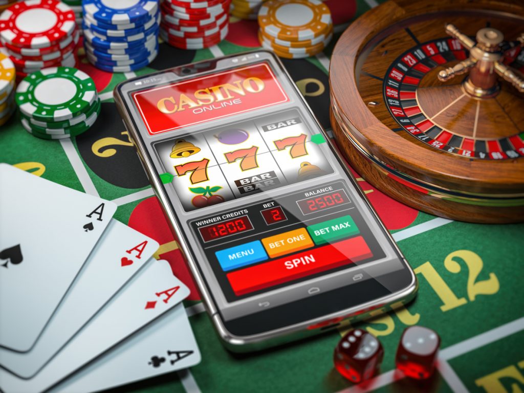 Casino online. Smartphone or mobile phone, slot machine, dice, cards and roulette on a green table in casino. 3d illustration